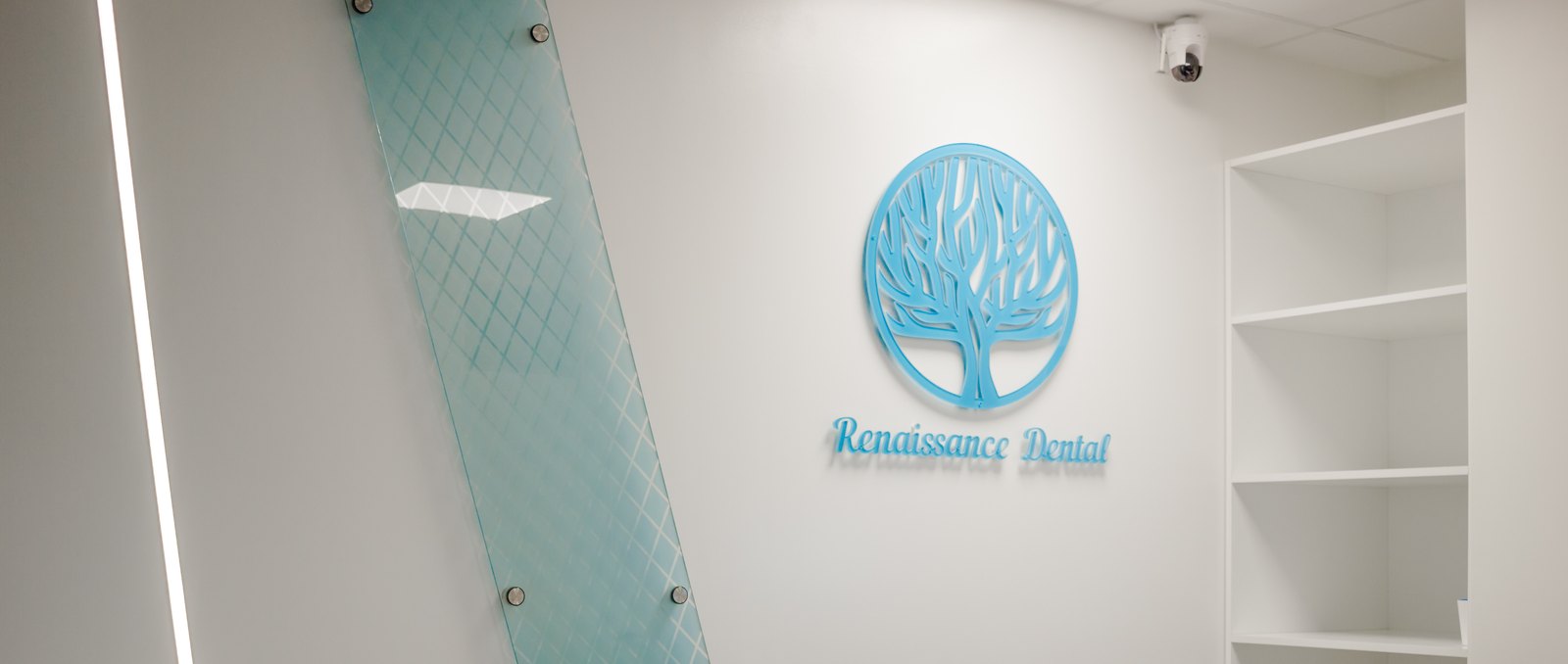 Receptionsvägg med klinikens logga, en glasskiva och hyllor